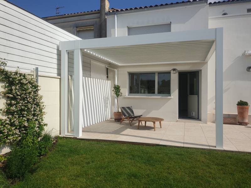 Au Cap Ferret, pergola bioclimatique haut de gamme 4x4 blanche en aluminium adossée au mur par